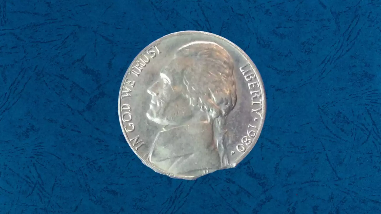 1980 Jefferson nickel struck on a copper cent planchet showing smaller diameter and reddish-brown copper color alongside a normal nickel for comparison